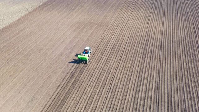 Russia, the Urals. Planting potatoes on the field with a combine and tractor. Spring. Drone footage