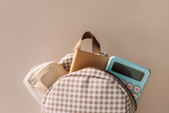 School backpack with notebook and blue calculator, stylish back to school background.