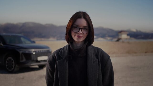 A beautiful young woman is standing on a sunny beach next to her favorite crossover SUV, smiling at the camera.