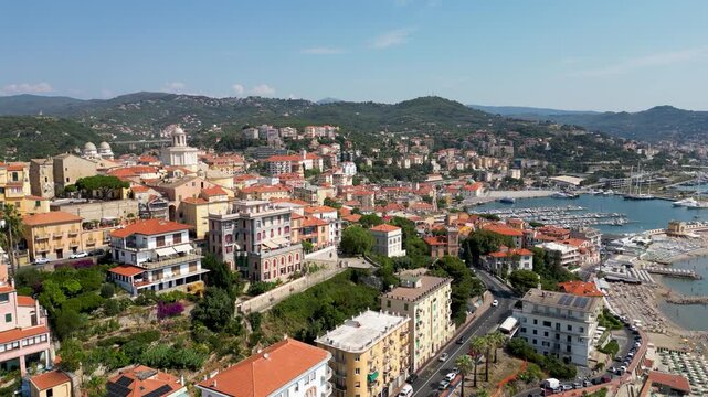 Aerial drone footage of Porto Maurizio historic quarter in Imperia featuring colourful houses perched on promontory and San Maurizio Cathedral on sunny day in Liguria Italy
