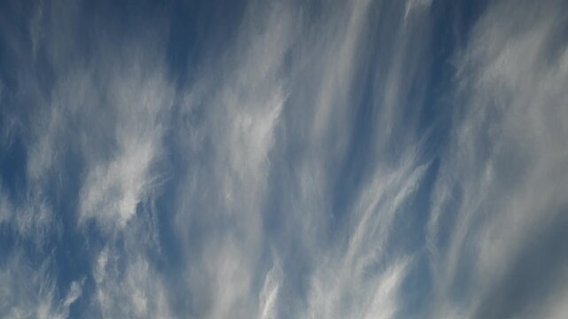 Timelapse of wispy white summer clouds gliding across a bright blue sky
