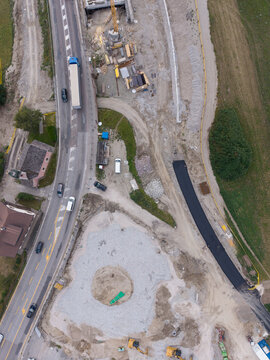 Bruneck, Trentino-Alto AdigeS, Italy - 27 July 2026: Aerial view of road construction site with heavy machinery, fresh asphalt, and civil engineering works next to a busy highway.