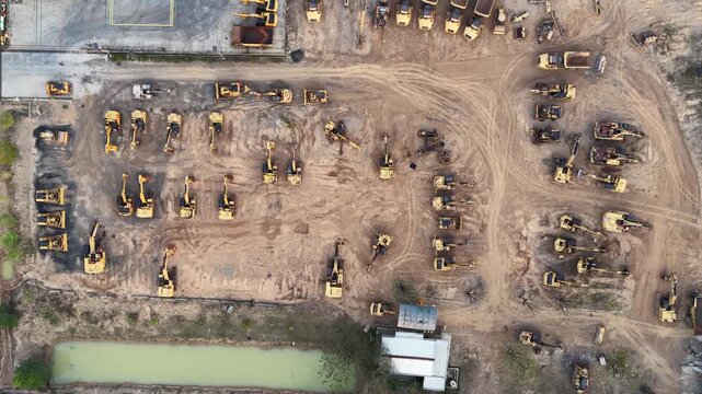 Rows of yellow excavators and trucks parked on dirt ground during the day in Banjarbaru
