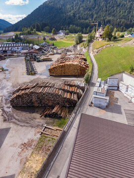 Bruneck, Trentino-Alto Adige, Italy - 27 July 2026: Aerial view of a sawmill facility with large stacks of timber logs, industrial buildings, and surrounding mountainous landscape.