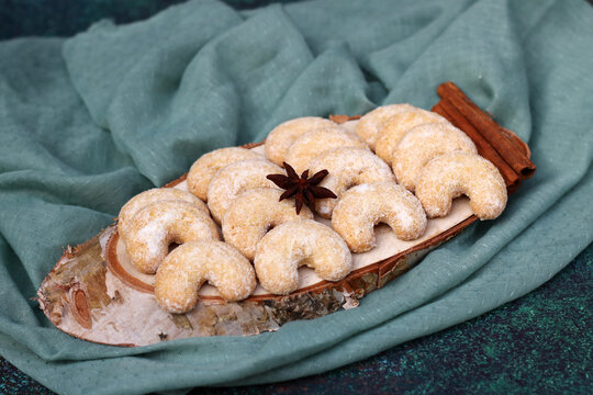 Vanillekipferl traditionelles Weihnachtsgeb&auml;ck auf einem Holzbrett mit Sternanis und Zimtstangen.