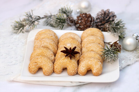 Vanillekipferl traditionelles Weihnachtsgeb&auml;ck auf einem Teller dekoriert mit Tannenzweigen.