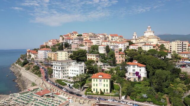 Aerial drone footage of Porto Maurizio historic quarter in Imperia featuring colourful houses perched on promontory and San Maurizio Cathedral on sunny day in Liguria Italy