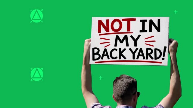 Protester holds a handmade Not in My Backyard sign over green screen, illustrating NIMBY opposition to unwanted development or local projects. Tracking points for background integration. 15294