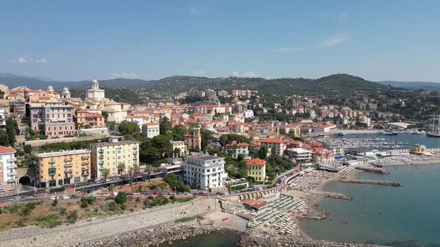 Aerial drone footage of Porto Maurizio historic quarter in Imperia featuring colourful houses perched on promontory and San Maurizio Cathedral on sunny day in Liguria Italy