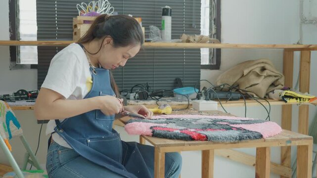 A focused individual creates a textile art piece using vibrant colors and various materials, combining creativity with craftsmanship in a cozy indoor space.