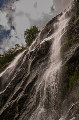 Powerful waterfall cascades down a steep, mossy cliff face © Ryszard