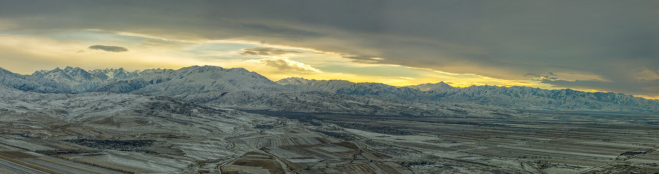 Panoramic Snow-Capped Mountain Range with Valley and Dramatic Sky