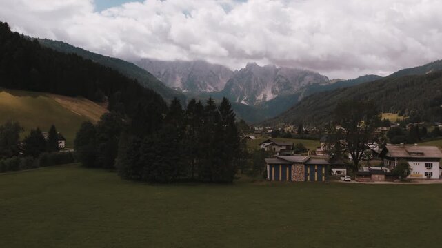 Drone flight over Alpine village with mountains in background