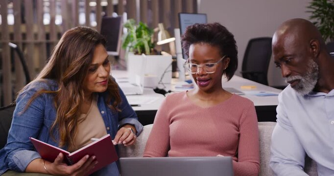African American team in office center woman scrolling laptop reviewing left holding notebook