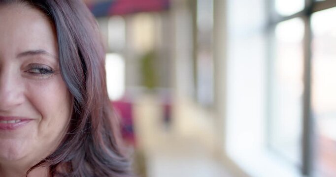 Adult woman shifting subtle smile into open laugh after off-camera cue by windows, copy space