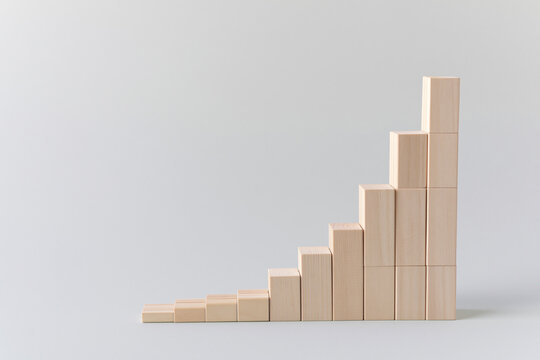 Rising bar chart of wooden blocks turning into a staircase growth concept