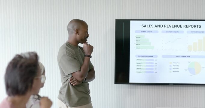 Diverse team seeing sales slide lead stepping to screen pointing charts in meeting reviewing sales