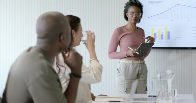 Diverse team watching slide update as African American woman showing adoption, pointing with tablet