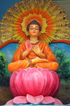 Colorful statue of Buddha avatar of Vishnu meditating on a lotus pedestal inside a Hindu temple niche.