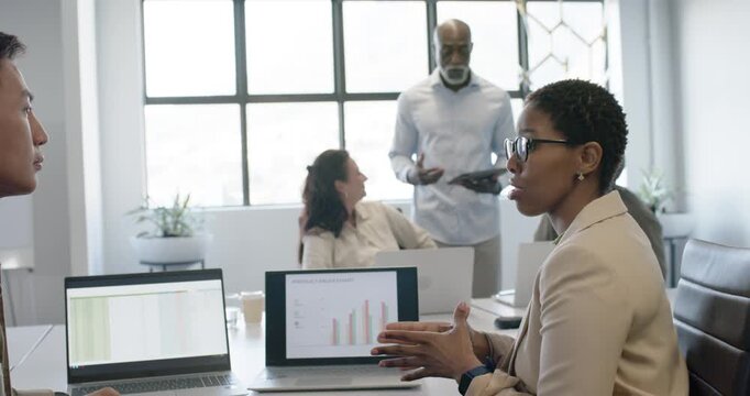 Diverse team African American woman showing chart at table as senior coming with tablet urging turn