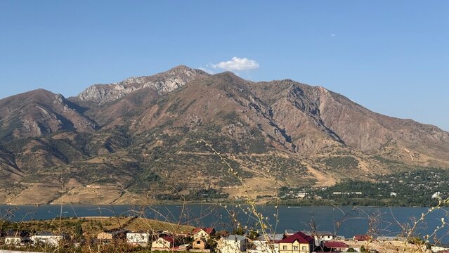 Mountain landscape overlooking Charvak Reservoir near Tashkent, Uzbekistan, with a small village beneath the rugged mountains.