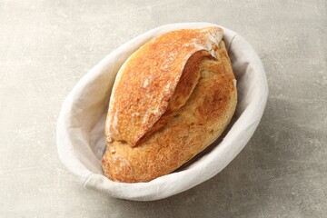 Naklejka premium Loaf of fresh bread in basket on gray textured table, closeup