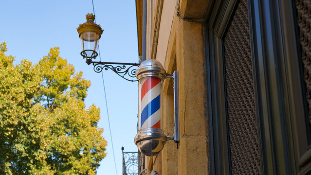 Traditional barber pole sign attached to a building facade in Metz, France