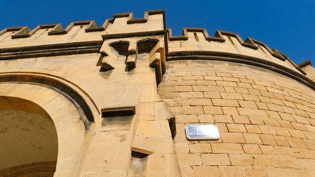 Porte des Allemands showing its fortified stone architecture and crenellated wall against a blue sky