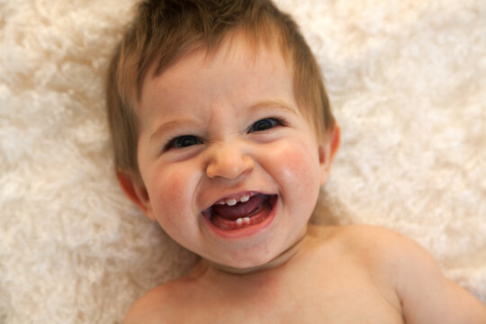 Portrait of a one year old boy with blue eyes and blonde hair. Horizontal shot, laughing