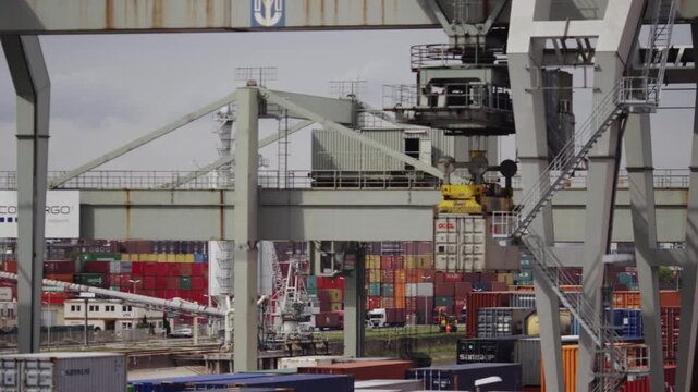 Gantry crane lifting cargo container at busy shipping port