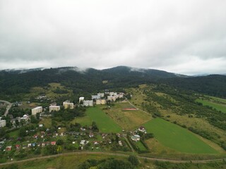 Krynica-Zdrój - Polska Panorama miasta i okolicznych gór nagrana dronem. Jaworzyna Krynicka, Góra Parkowa, miasto, Beskidy, lasy, mgła i chmury nisko osadzone opadające na góry © Konrad