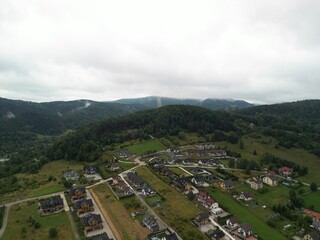 Krynica-Zdrój - Polska Panorama miasta i okolicznych gór nagrana dronem. Jaworzyna Krynicka, Góra Parkowa, miasto, Beskidy, lasy, mgła i chmury nisko osadzone opadające na góry