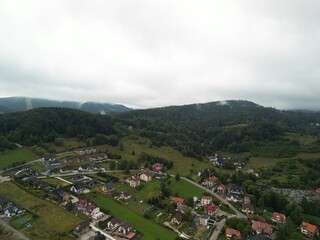 Krynica-Zdrój - Polska Panorama miasta i okolicznych gór nagrana dronem. Jaworzyna Krynicka, Góra Parkowa, miasto, Beskidy, lasy, mgła i chmury nisko osadzone opadające na góry © Konrad