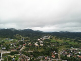 Krynica-Zdrój - Polska Panorama miasta i okolicznych gór nagrana dronem. Jaworzyna Krynicka, Góra Parkowa, miasto, Beskidy, lasy, mgła i chmury nisko osadzone opadające na góry © Konrad