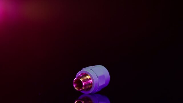 Purple metal pipe fitting rotating on dark reflective surface