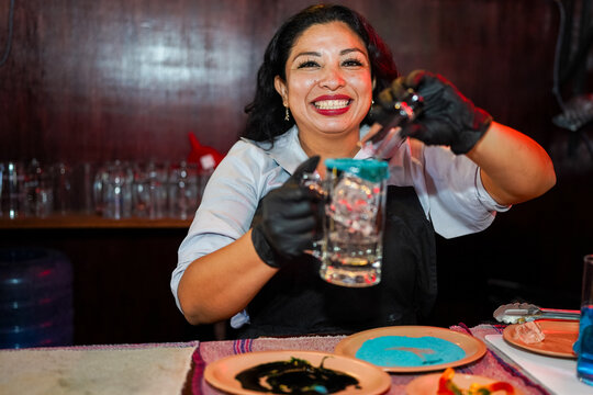 Hispanic woman bartender preparing drink rimming glass at bar