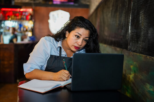 Latin woman entrepreneur planning small business in cafe