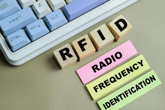 Concept of RFID - Radio Frequency Identification write on sticky notes isolated on Wooden Table.