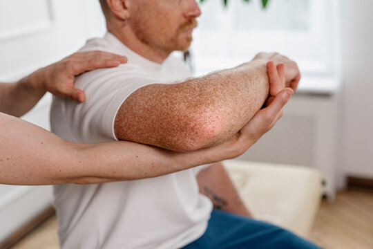 Physiotherapist examines patient joint during therapy in hospital setting