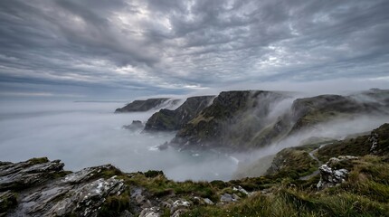 Fototapeta premium Coastal British sea fog creeping over Devon cliffs in early morning grey light.
