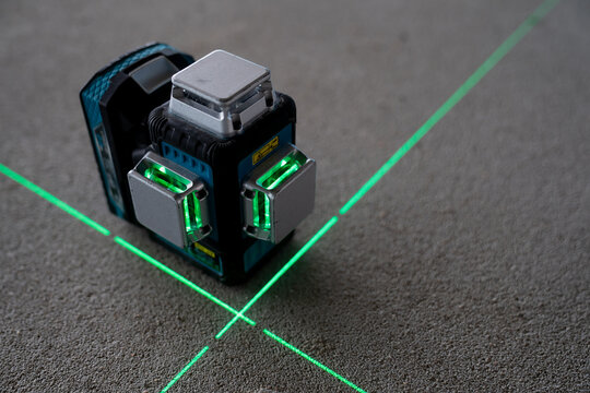 Compact digital multi line green beam laser level projecting 360 degree crosshair lines representing precision measurement and layout tools