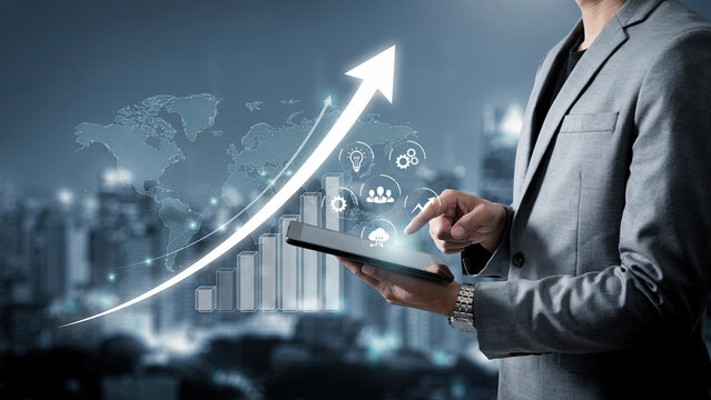 Businessman holding digital tablet with glowing financial growth charts and icons for corporate business planning