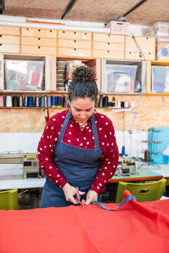 Artisan woman cutting fabric for upholstery in workshop