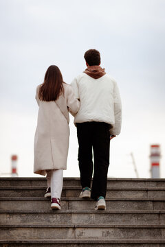 Rear view of a couple walking up outdoor steps on a cloudy day