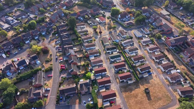 Aerial drone footage of Winnersh village in Berkshire, England, showcasing residential areas, green spaces, roads, local development, and surrounding countryside on a bright summer day.