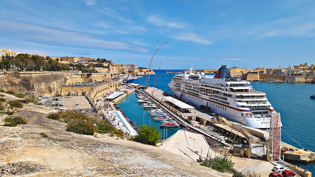 Cruise ship docked in Valletta Grand Harbour, Malta, with marina, historic fortifications and bright blue water under sunny Mediterranean sky: Valletta, Malta - April 4, 2026