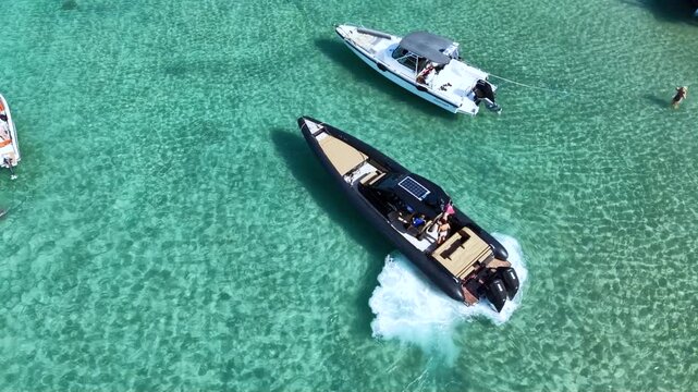 Top-down aerial view of a luxury inflatable motorboat floating over crystal clear turquoise sea, with visible seabed patterns and large copy space creating an idyllic summer travel scene.