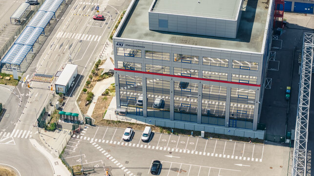 Crolles, France - 01 August 2026: Aerial view of the STMicroelectronics semiconductor manufacturing campus, featuring the main office building, entrance gate, and parking area.