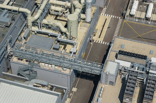 Crolles, France - 01 August 2026: Aerial view of the Soitec semiconductor manufacturing campus featuring industrial process piping, elevated utility bridges, and technical cooling infrastructure.