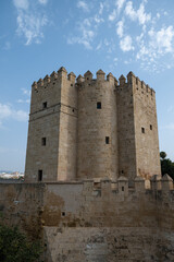 Naklejka premium The magnificent architecture of the historic Calahorra Tower (Torre de la Calahorra) in Seville and the surrounding city walls, set against a clear blue sky.